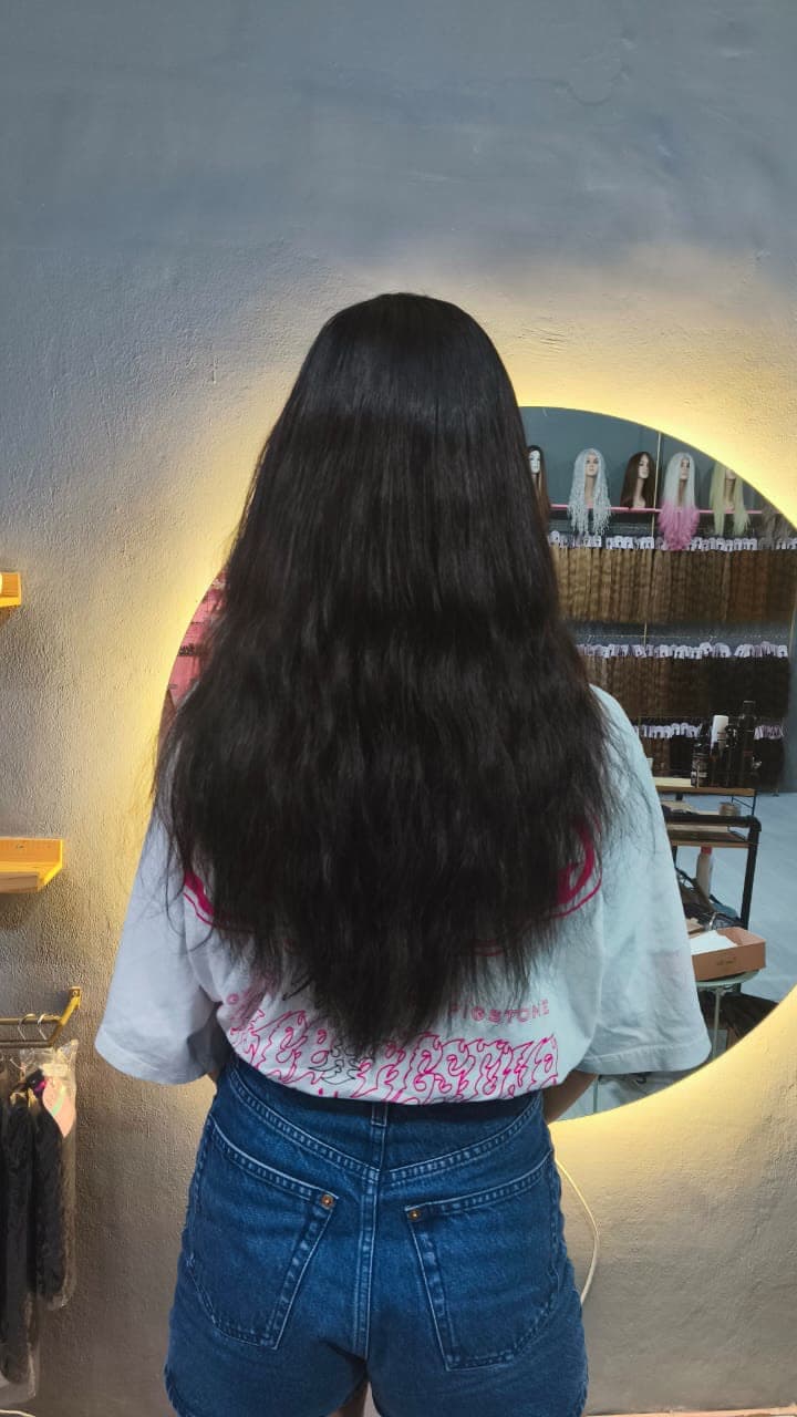 Same client after — long dark wavy extensions, full transformation