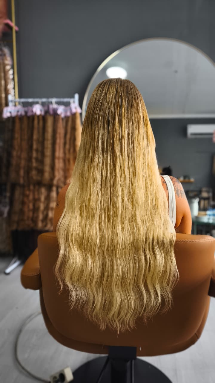 Same client after — long, full blonde waves past the chair back, Keratin Bond double 100 g