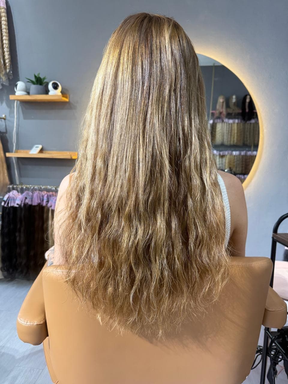 Same client after — long highlighted waves well past the chest