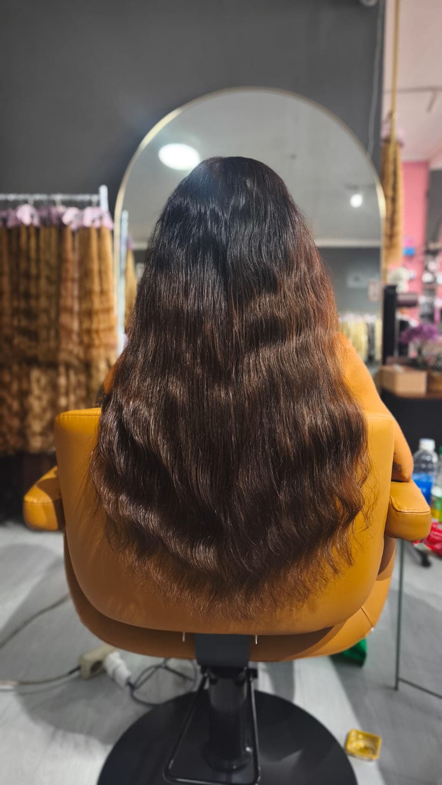 Same client after — long chocolate-brown waves past the chair back, Weft double 150 g