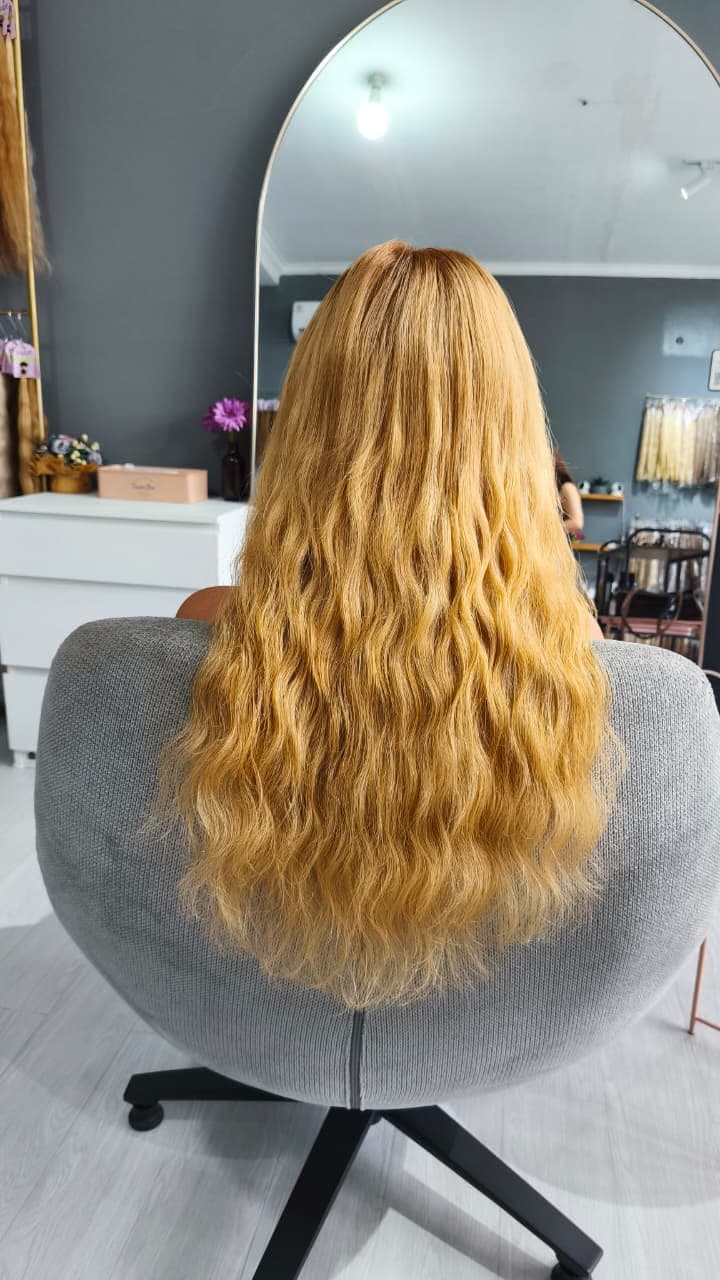 Same client after — long honey-blonde wavy extensions