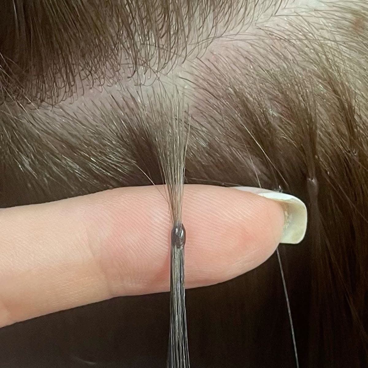A single Keratin Bond fitted at the root, held between fingertips
