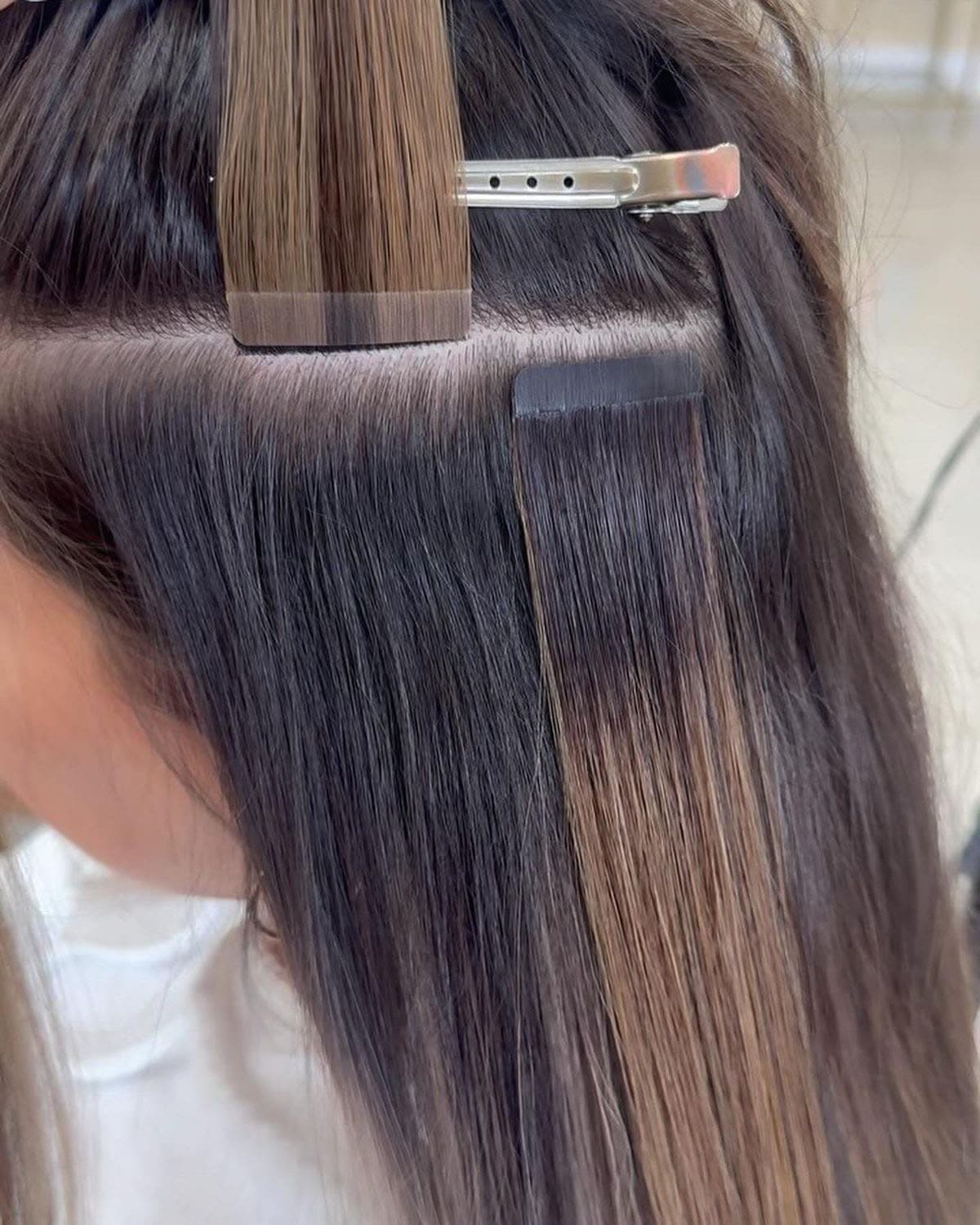 Tape-In weft sandwiched at the root of dark hair